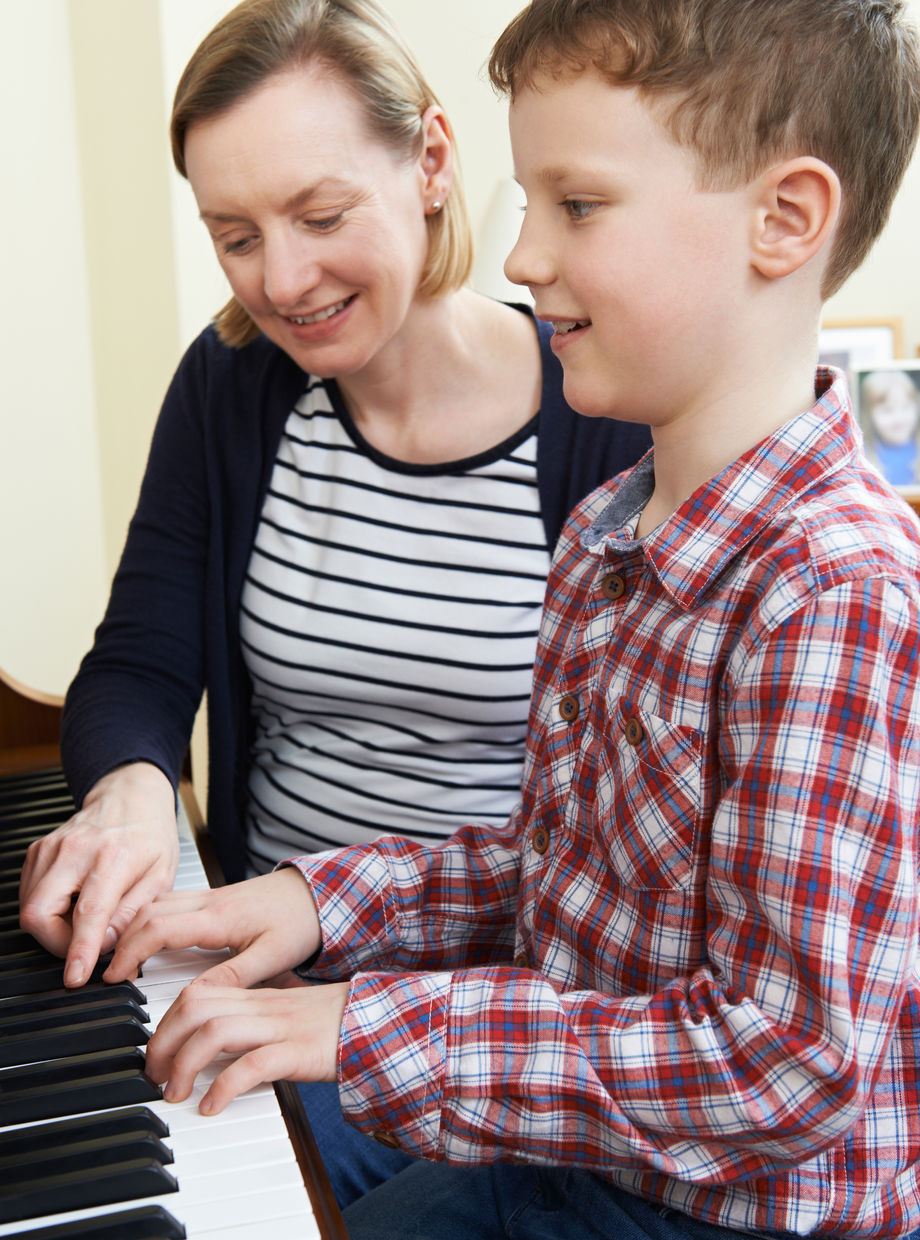 A teacher and a young student playing at a keyboard